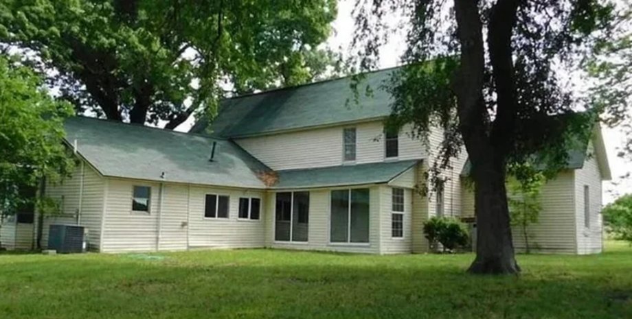 Деревянный дом с зеленой крышей, окруженный деревьями, который позже уничтожил торнадо