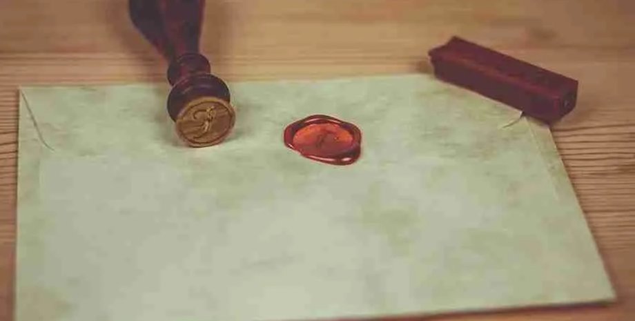 Конверт с красной сургучной печатью на деревянном столе