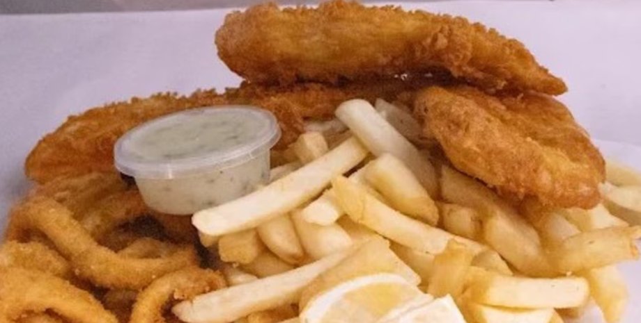 Жареная рыба, картофель фри, кальмары и соус тартар на тарелке в ресторане Перта