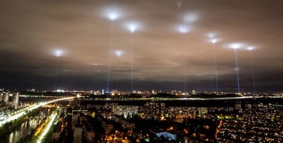 Светящиеся лучи в облаках над современным мегаполисом, напоминающие наблюдение НЛО