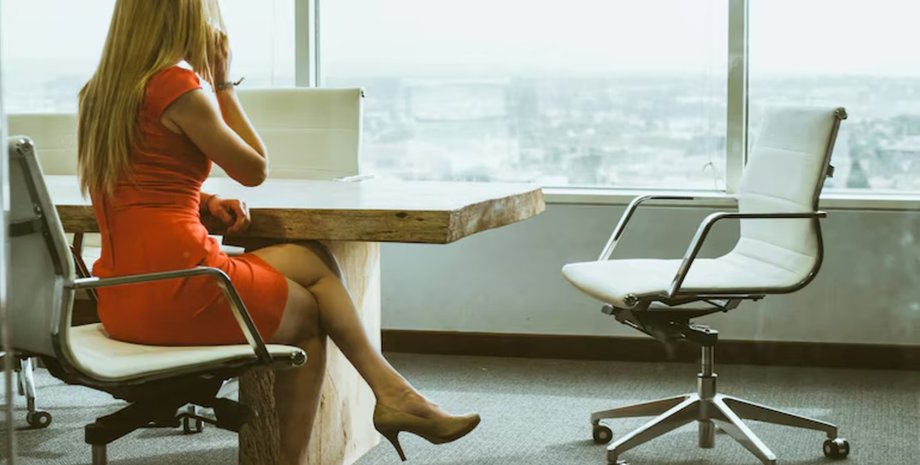 Женщина в красном платье сидит в офисе за столом