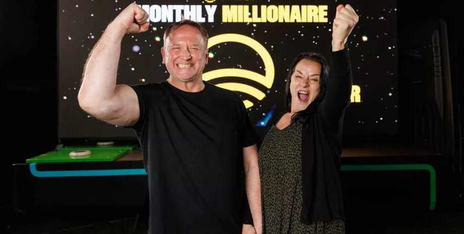 Муж и жена радостно поднимают руки после объявления о победе в миллионном розыгрыше Omaze