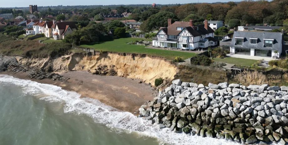Вид с высоты птичьего полета на дома в Саффолке, расположенные у края обрыва, размываемого морем