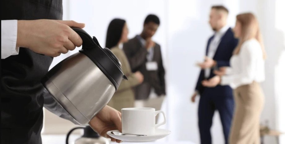Человек наливает кофе на фоне разговаривающих сотрудников